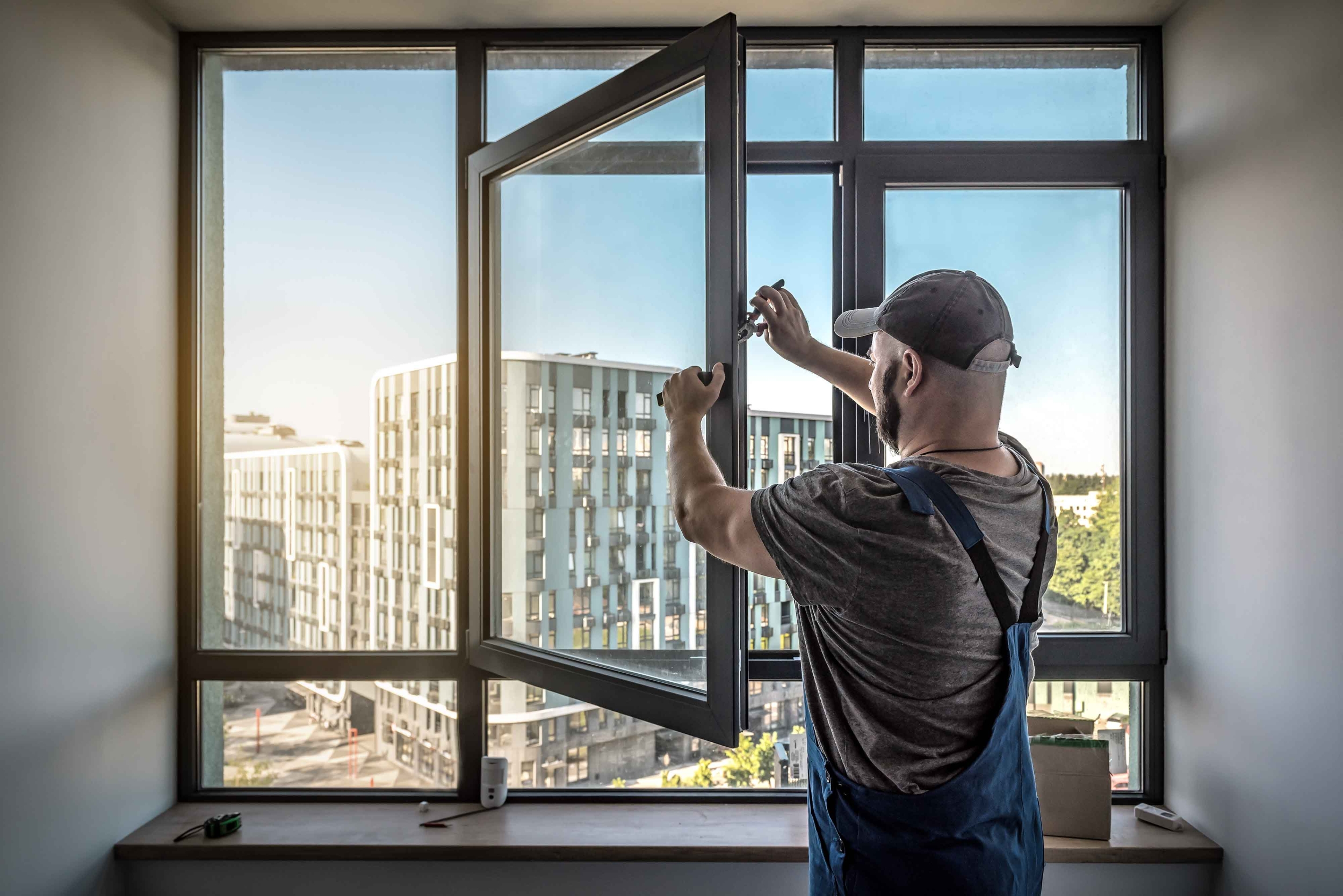 Tømrer i gang med udskiftning af vindue i moderne lejlighed – professionelt tømrerarbejde